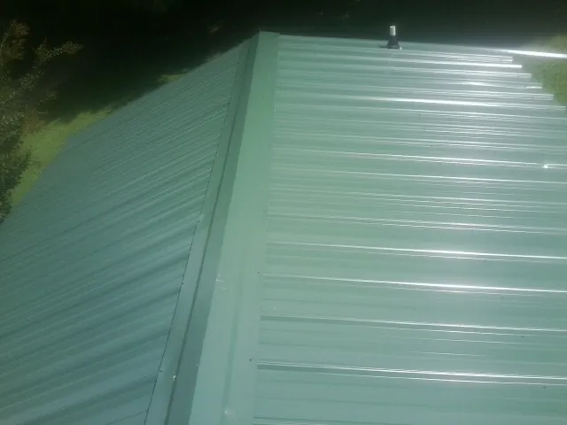 New green metal panels meeting at the ridge of a roof — Flat Roof Repair work by our crew in Elizabethport