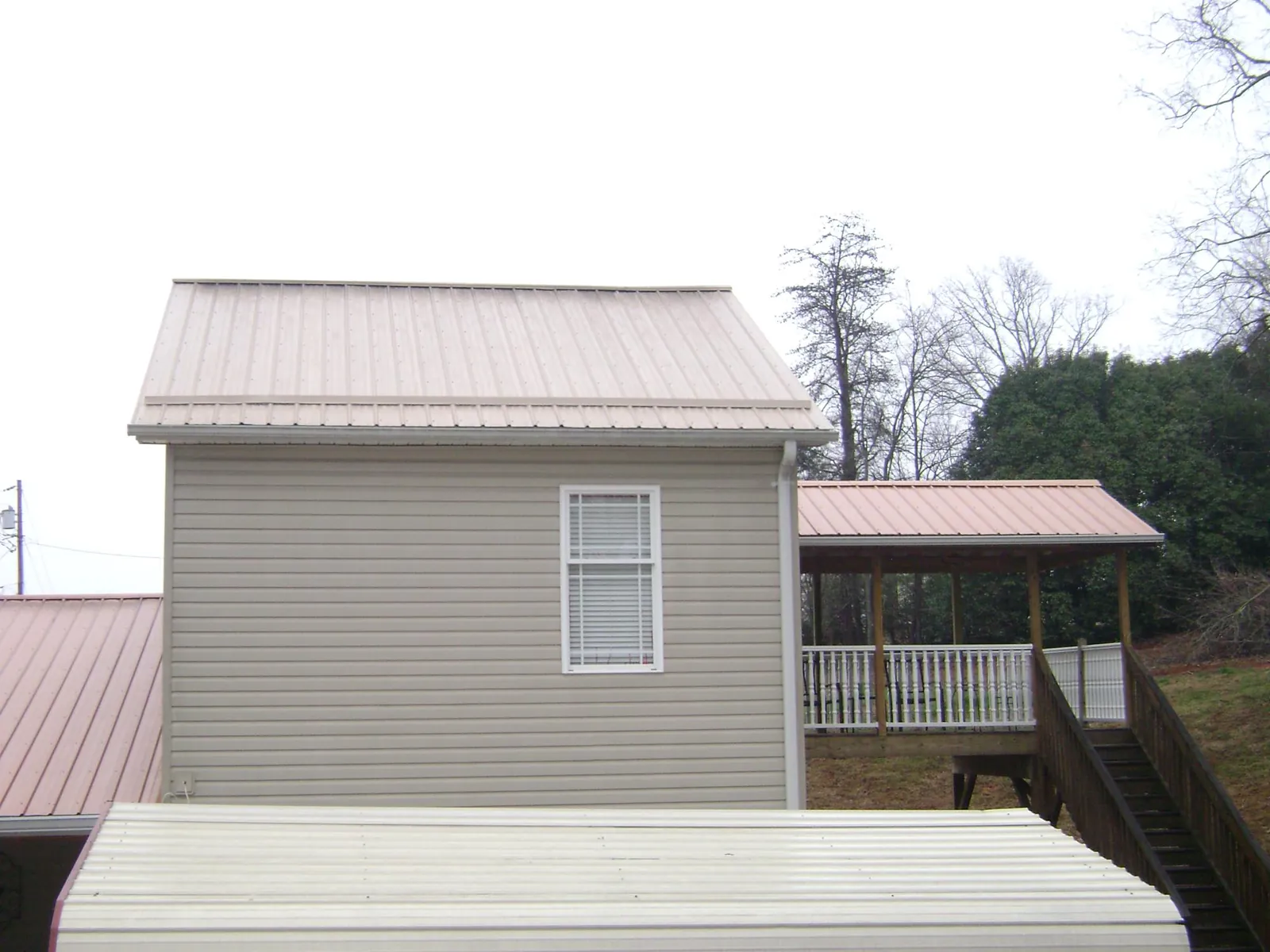 Tan metal roofs on a two story addition and attached porch, from a Roof Replacement job in Elizabethport