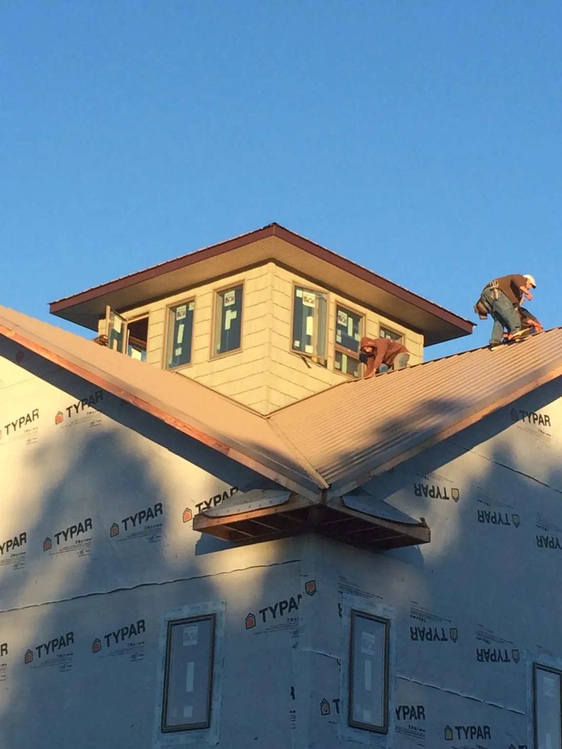 Roofers working around a rooftop cupola on a new metal roof at sunset — Roof Waterproofing in Elizabethport by Roofing Brothers